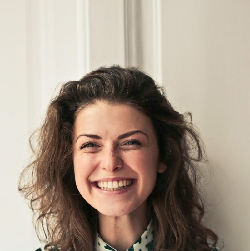 Portrait of a joyful brunette woman with a vibrant smile indoors, capturing happiness and positivity.